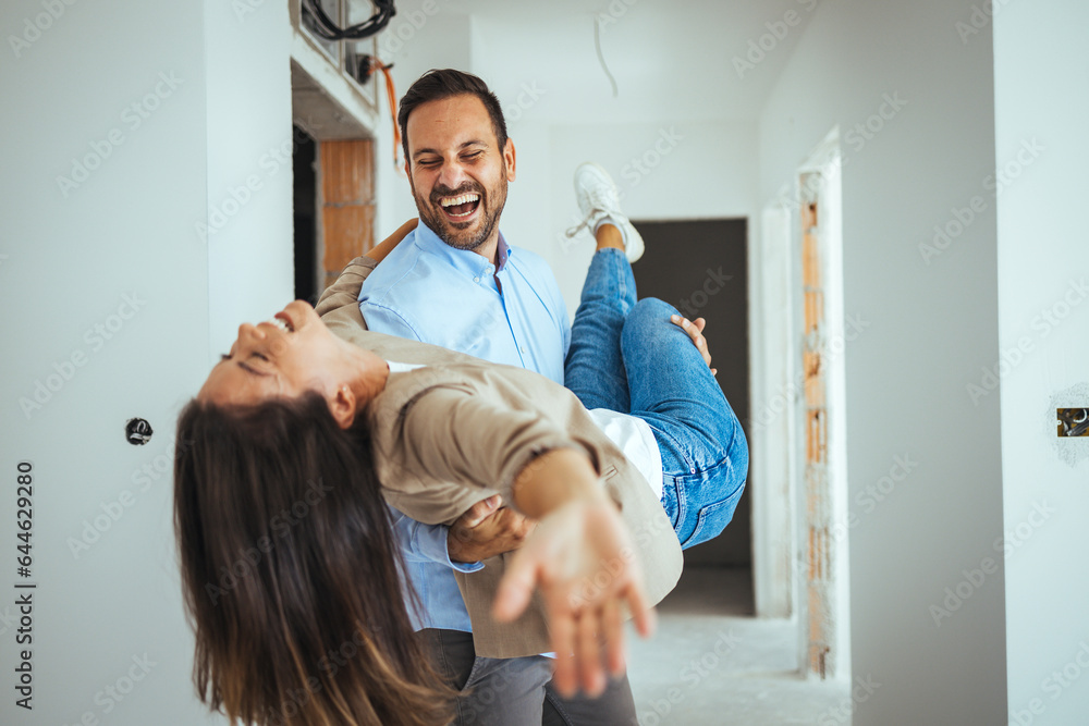Dancing Couple Happy With Apartment Choice. Relocation, real estate, rent concept. Happy and Excited Young Couple Look Around In Wonder at their Newly Purchased Dancing Couple Happy With Apartment Choice. Relocation, real estate, rent concept. Happy and Excited Young Couple Look Around In Wonder at their Newly Purchased