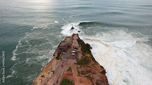 Top-down Aerial view of the people on the Fort of Sao Miguel Arcanjo Lighthouse in Nazare, Portugal. Nazare is famously known for having the biggest waves in the world. photo