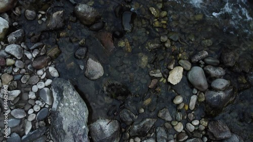 Camera looks down on water running through stones of a small stream photo