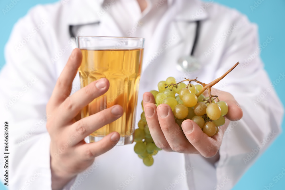 Male doctor with glass of juice and grape on blue background, closeup Male doctor with glass of juice and grape on blue background, closeup