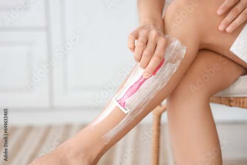 Obraz na plátně Young woman shaving legs in bathroom, closeup