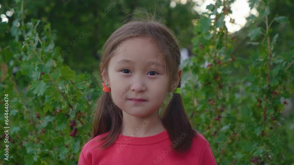 A cute girl picks up a fruit, points to the camera and eats A cute girl picks up a fruit, points to the camera and eats