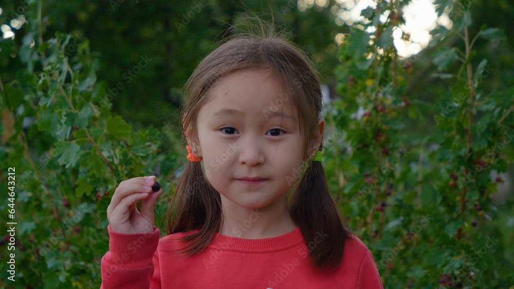 A cute girl picks up a fruit, points to the camera and eats A cute girl picks up a fruit, points to the camera and eats