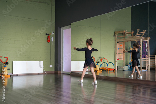 Child girl standing in black sport bodysuit in dancing studio during training posture. 4 5 years old preschool age. Healthy physical development 