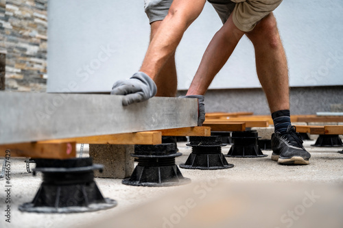 Low angle view of a man leveling a supportive construction for wooden terrace