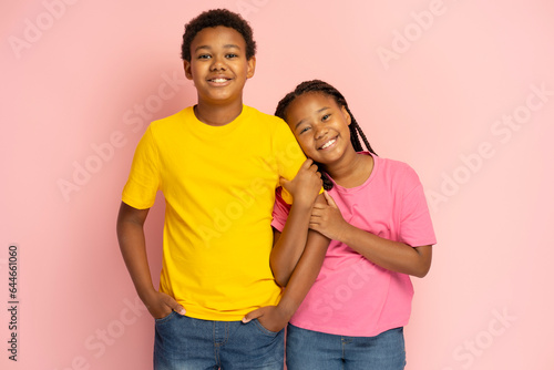 Tableau sur toile Portrait of smiling African American children, brother and sister standing together isolated on pink background