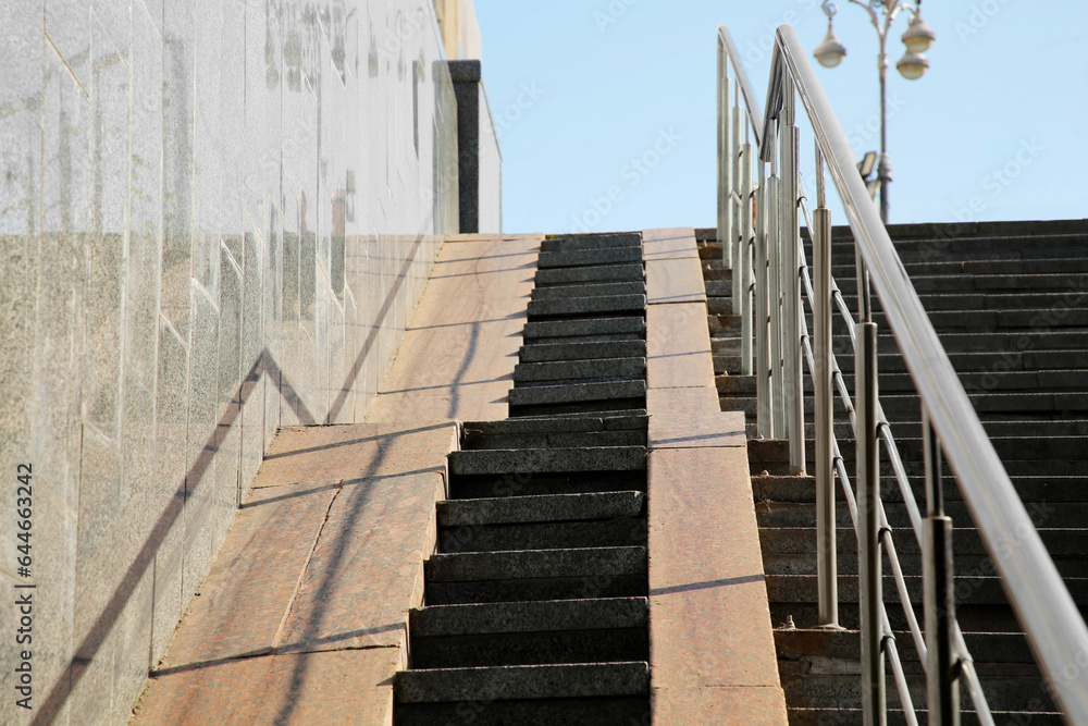 Staircase and ramp with metal handrail near building outdoors Staircase and ramp with metal handrail near building outdoors