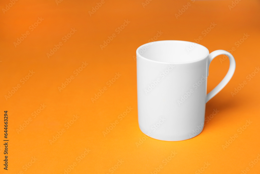 One white ceramic mug on orange background, space for text One white ceramic mug on orange background, space for text