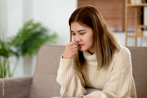 asian young woman sitting on the sofa thinking and looking seriously