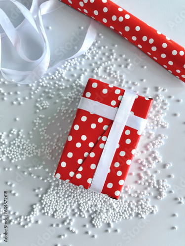 Flat lay overhead of gift wrapped in red with white polka dots wrapping paper and white ribbon during Holidays giving season.
