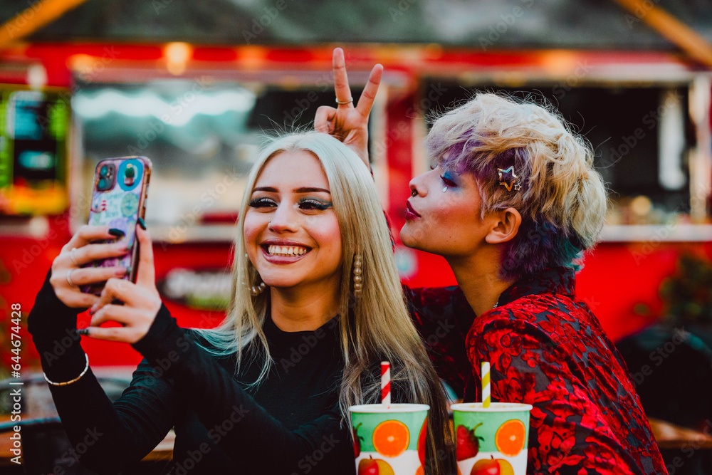 Friends taking selfies with a mobile phone while enjoying having fun together outdoors.