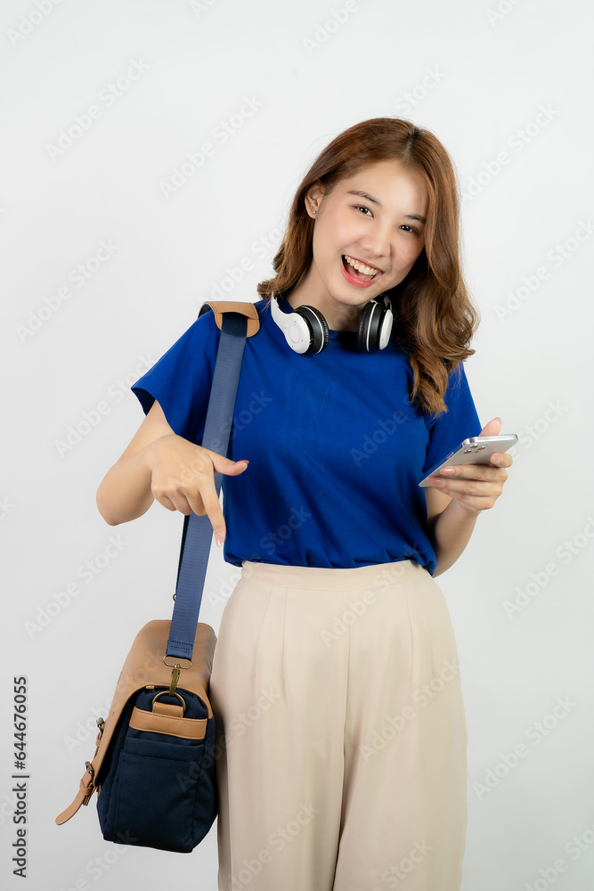 Asian girl using smartphone in blue shirt and backpack on background while standing and mobile phone isolated on white background Asian girl using smartphone in blue shirt and backpack on background while standing and mobile phone isolated on white background