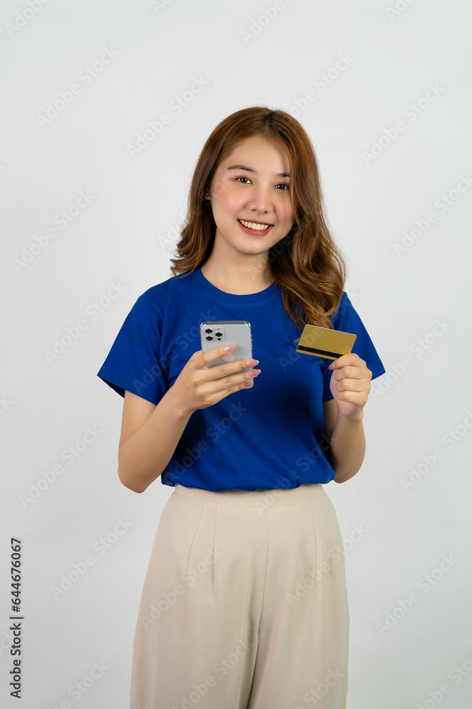 Beautiful young woman uses credit card and mobile phone to make online banking transactions. Holding credit card and mobile phone while looking at camera isolated on white background. Beautiful young woman uses credit card and mobile phone to make online banking transactions. Holding credit card and mobile phone while looking at camera isolated on white background.