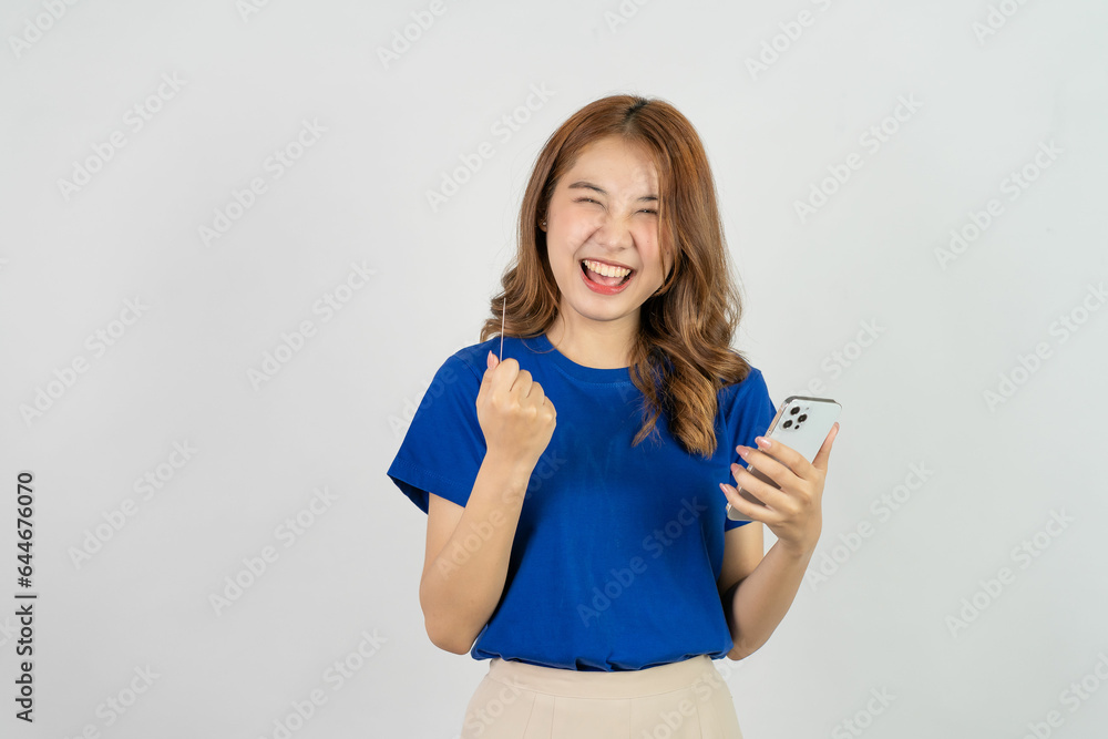 Pretty happy asian teenage girl using mobile phone playing music from smartphone application, happy smiling while listening streaming music against white background, technology concept Pretty happy asian teenage girl using mobile phone playing music from smartphone application, happy smiling while listening streaming music against white background, technology concept