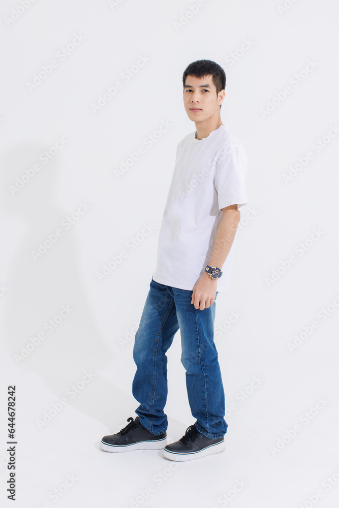 Portrait isolated cutout studio full body shot Asian handsome cool male fashion model in casual fashionable t shirt and blue jeans standing holding hands in pockets look at camera on white background Portrait isolated cutout studio full body shot Asian handsome cool male fashion model in casual fashionable t shirt and blue jeans standing holding hands in pockets look at camera on white background