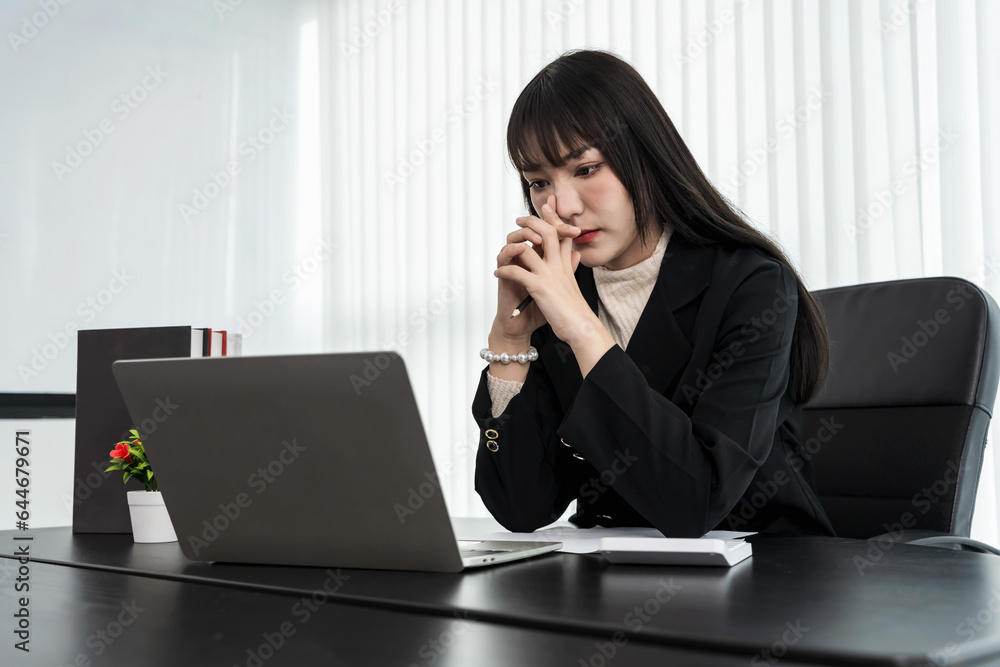 Young Asian businesswoman looking and working on computer laptop in office Young Asian businesswoman looking and working on computer laptop in office