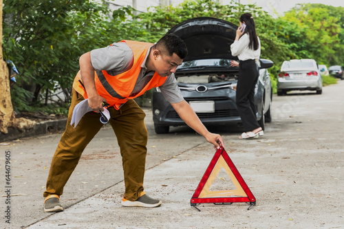 Man putting triangle warning sign with accident on the road