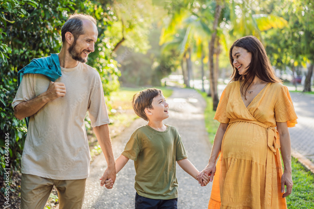 A loving family enjoying a leisurely walk in the park - a radiant pregnant woman after 40, embraced by her husband, and accompanied by their adult teenage son, savoring precious moments together