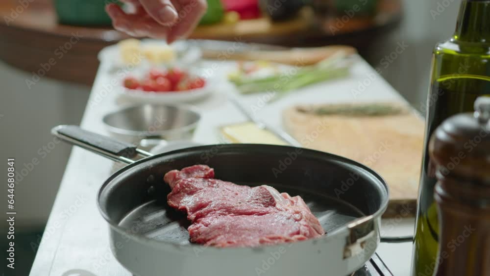 Hands of chef placing meat steak on hot grill pan while preparing food in the kitchen. Close-up view, impersonal shot Hands of chef placing meat steak on hot grill pan while preparing food in the kitchen. Close-up view, impersonal shot