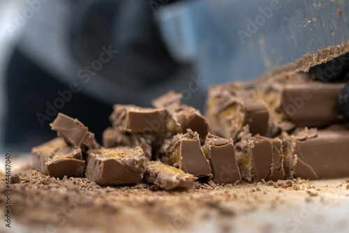 chef cutting sweet chocolate bars with caramel filling , fudge candy for cheesecake preparation photo