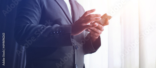 Businessman using smartphone, success after monthly meeting, corporate window background, success concept