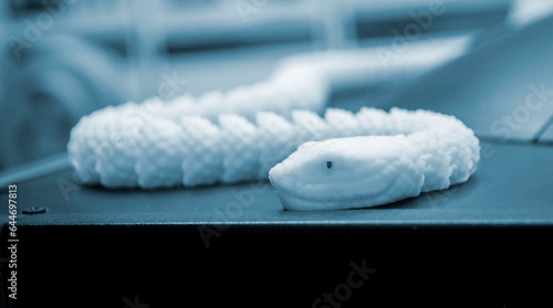 Art object printed on 3D printer. Prototype small snake. Model printed on 3D printer from melted plastic. Object printed close-up. Concept new modern innovation printing technology