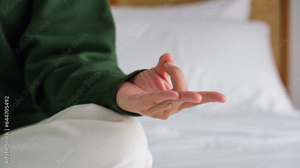 Closeup of a woman meditating or practicing yoga in lotus pose on the bed
