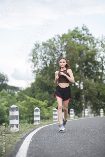 Young sporty woman jogging in the green park in the evening