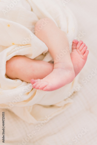A close-up of a newborn baby's feet. The infant is wrapped up in a white blanket with only his feet showing. 