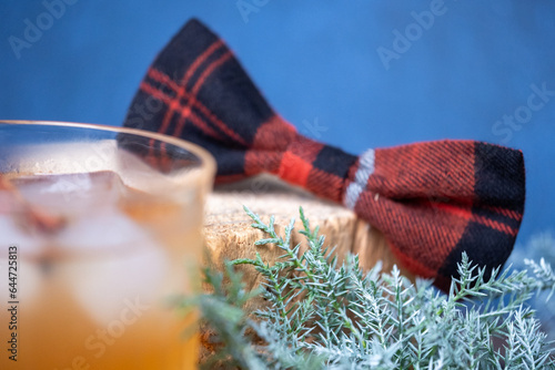 The Christmas mood with red black checkered bow on a wooden pad and juniper branch in the background. Copy space