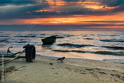 Coastal landscape at dawn with anchored fishing boat on sandy beach of the Ba...