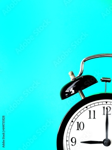 Black retro alarm clock at 9 nine o clock on a blue background with copy space to add text 9am 9pm photo