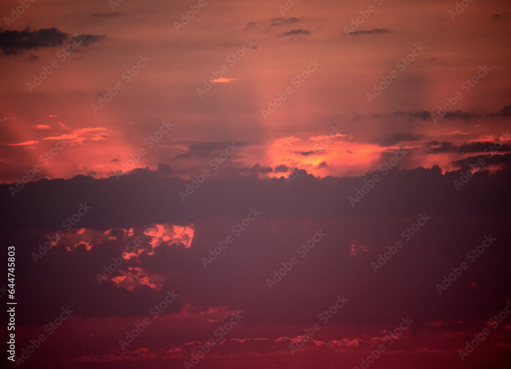 fiery sunset, colorful clouds in the sky and sunrays from behind the clouds