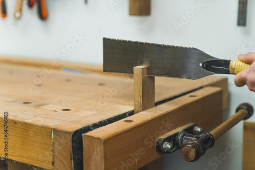 Using workbench vise for cutting wood with a handsaw . High quality photo