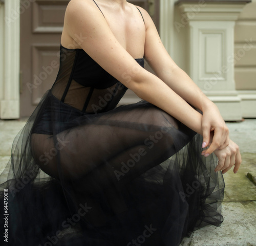 a 30-year-old girl sits near the house in a black, transparent, revealing dress. Style and elegance, fatal girl, photo shoot in a black dress, cheating