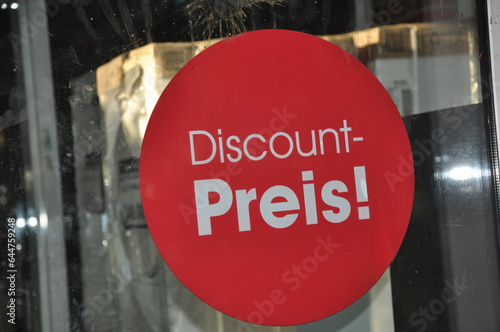 Discount Preis! Rundes Klebeschild auf der Glastür vom Supermarkt in rot und mit weißer Schrift.