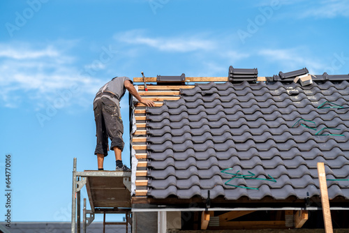 builder on the roof of a family house, building a roof covering from ceramic tiles