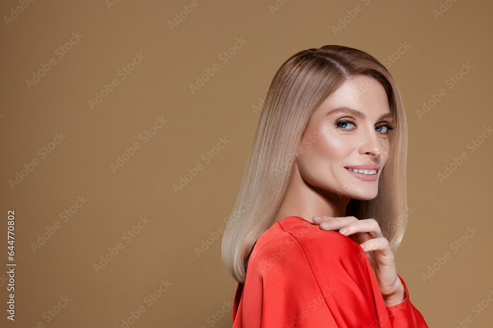 Portrait of stylish attractive woman with blonde hair smiling on dark beige background, space for text Portrait of stylish attractive woman with blonde hair smiling on dark beige background, space for text