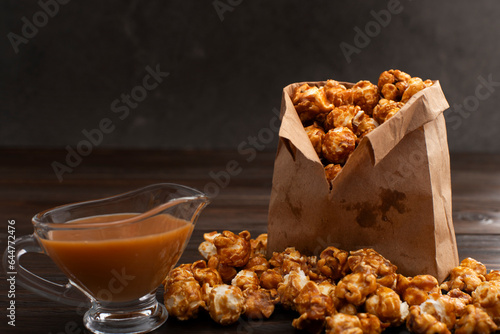 Obraz na płótnie Caramelized popcorn in paper bag on wooden kitchen table w salonie