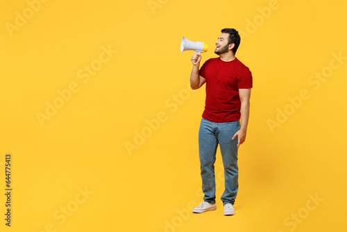 Full body young happy Indian man wears red t-shirt casual clothes hold in hand megaphone scream announces discounts sale Hurry up isolated on plain yellow orange background studio. Lifestyle concept.