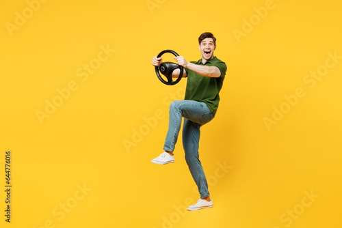 Full body side view surprised excited happy young happy man he wears green t-shirt casual clothes hold steering wheel driving car isolated on plain yellow background studio portrait Lifestyle concept © ViDi Studio