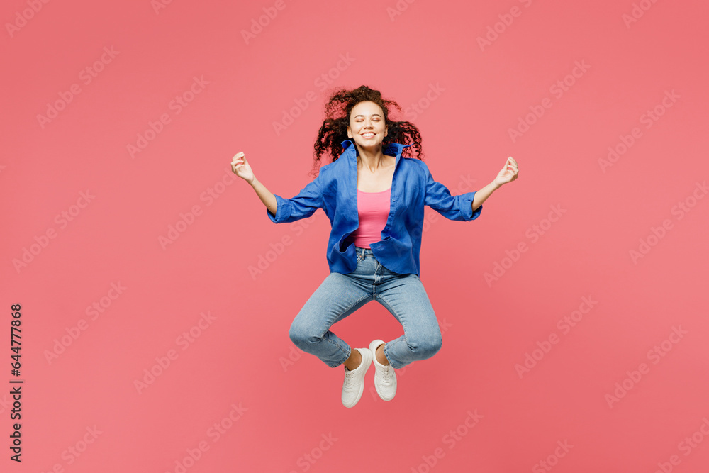 Full body young woman of African American ethnicity wear blue shirt casual clothes jump high hold hands in yoga om aum gesture relax meditate try calm down isolated on plain pastel pink background. Full body young woman of African American ethnicity wear blue shirt casual clothes jump high hold hands in yoga om aum gesture relax meditate try calm down isolated on plain pastel pink background.