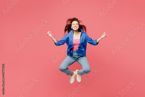 Full body young woman of African American ethnicity wear blue shirt casual clothes jump high hold hands in yoga om aum gesture relax meditate try calm down isolated on plain pastel pink background.