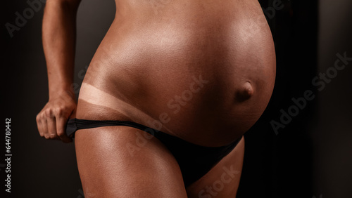 Pregnant woman pulls back her panties showing instant tan. 
