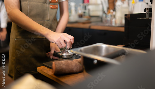Cropped image of female barista using coffee machine in coffee shop © Wosunan