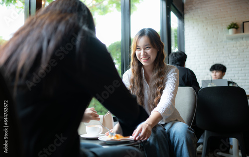 Young asian woman sitting in cafe and drinking coffee with friends.