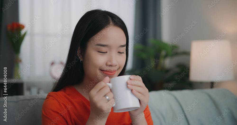 Asian woman drinking a coffee while sitting on the sofa Asian woman drinking a coffee while sitting on the sofa