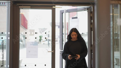 Woman strolls through hallway entering a modern building