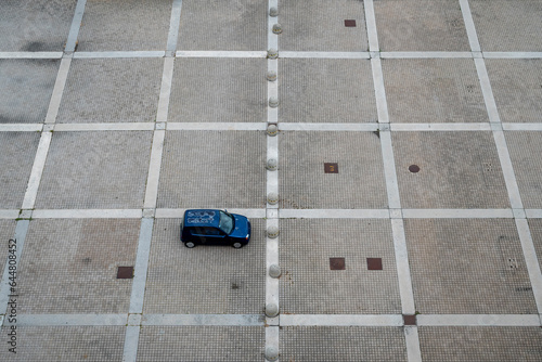 Parcheggio deserto Una sola automobile parcheggiata, isolata. Ripresa dall'alto fra le linee geometriche del pavimento.