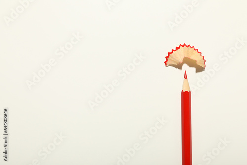 Red pencil with shavings on a light background.